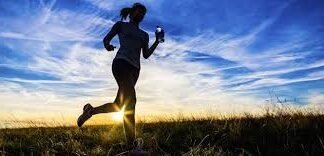 mujer corriendo por la naturaleza en un amanecer pensando en Comparativa de Masajeadores para Deportistas para reponer la musculatura